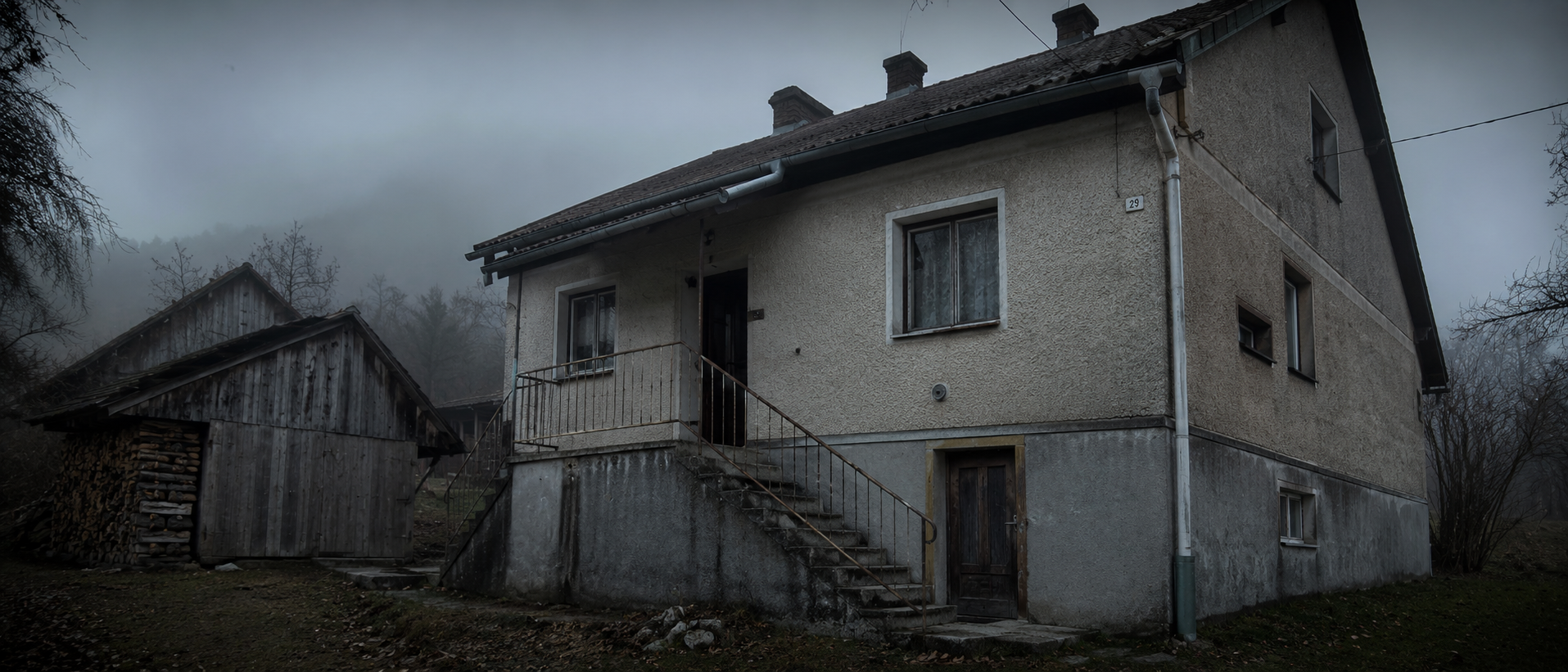Starý oravský dom s drevárňou, prikrčený v hmle pod horou.